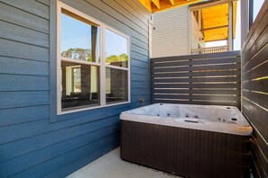 Banheira de hidromassagem perto de janela com vista para móveis de exterior.
