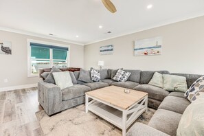 A living room with a sectional sofa, a coffee table, and artwork on the walls. - Gorgeous Beachfront Luxury 6 BR Home | Elevator | Pet Friendly | Free Activities Including Free Golf (Oak Island)