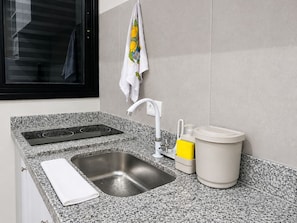 Eine moderne Küche mit einer Granit-Arbeitsplatte, einer Edelstahl-Spüle, einem weißen Wasserhahn und einem gelben Aufbewahrungsbehälter.