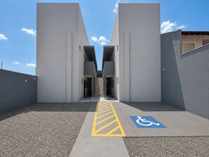 A building entrance with a ramp leading to a door, a wheelchair accessibility symbol, and a clear sky.