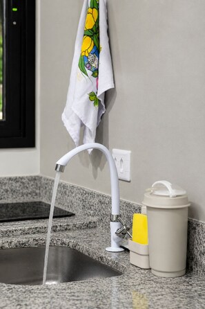 A bathroom sink with a modern faucet, a towel hanging on the wall, and a soap dispenser on the counter.