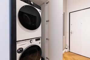 A laundry room with two stacked washing machines, a door, and a wooden floor. - Stunning Brand New 4BR 4BATH Center-Vatican (Rome)