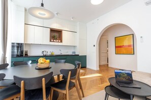 A modern kitchen with white cabinets, a dining table with chairs, and a laptop on a side table. - Stunning Brand New 4BR 4BATH Center-Vatican (Rome)
