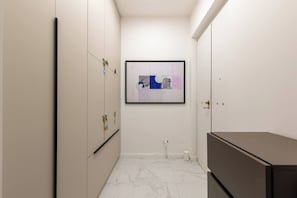 A narrow hallway with a framed artwork on the wall, a door with a brass handle, and a dark-colored cabinet. - Stunning Brand New 4BR 4BATH Center-Vatican (Rome)