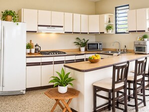 A kitchen with a central island, a microwave, a stove, and bar stools. - Casa Carmín-3BR & Pet Friendly- San Sebastian (San Sebastián)
