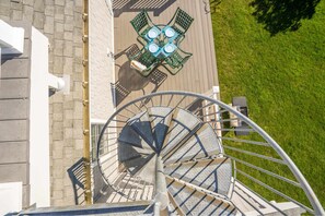 A spiral staircase with a metal railing, leading to a rooftop area with a table and chairs. - Moody Surfer - Coastal Retreat (Wells)