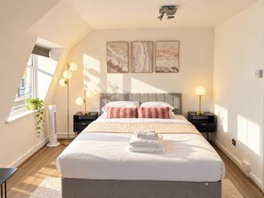 Ein modernes Schlafzimmer mit einem großen Bett, Nachttischlampen und Kunstwerken an der Wand.
