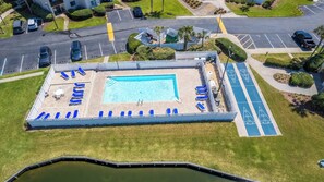 An aerial view of a swimming pool area with lounge chairs, a small pool, and a parking lot. - Bright 2BR Beach Condo | Free Chairs + Attractions (St. Augustine)