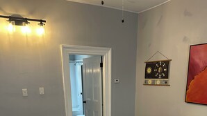 A room with a wooden floor, a dining table with chairs, a door leading to a bathroom, and a wall-mounted light fixture. - 1880 Yellow-Brick Cottage Executive Retreat (London)