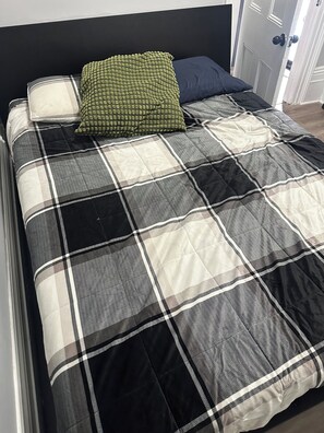 Ein Bett mit kariertem Überwurf und zwei Kissen.