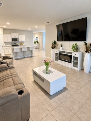 Ein modernes Wohnzimmer mit Fernseher, einem weißen Couchtisch mit einer Vase und einem beigen Sofa.