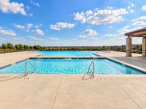 Une piscine avec un ciel bleu dégagé et une vue sur un quartier résidentiel en arrière-plan.
