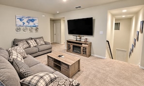 Ein Wohnzimmer mit Ecksofa, Couchtisch, Fernseher und Kamin.