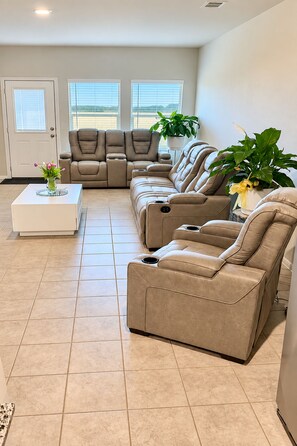 Un salon spacieux avec un canapé d’angle beige, une table basse blanche et une plante en pot.