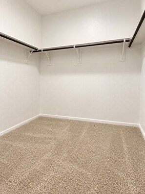 Ein Zimmer mit Teppichboden, weißen Wänden und einer Decke mit einem schwarzen Balken.