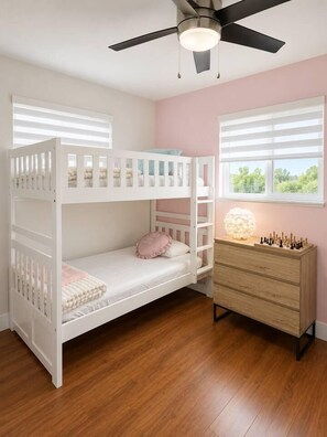 A bunk bed room with a ceiling fan, a dresser, and a window with blinds.