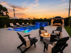 A poolside area with lounge chairs, a fire pit, and a covered seating area.