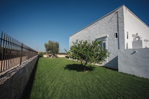 A modern building with a stone facade, a well-maintained lawn, and a metal fence. - Dimora Bellarosa - A Timeless Masseria with Infinity Pool (Puglia)