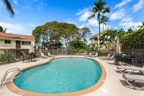 A swimming pool with lounge chairs and umbrellas, surrounded by palm trees and a clear sky. - Keauhou Palena #604 Kona Retreat With A/C (Kailua-Kona)