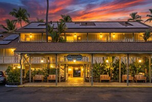 A hotel with a sign reading 'Kona Islander Inn,' featuring a covered entrance, outdoor seating, and solar panels on the roof. - Kona Islander Inn#251: Downtown Kona, Remodeled! (Kailua-Kona)