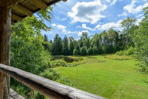 Une cabane en bois offrant une vue sur un paysage boisé et un étang.