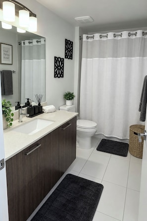 A modern bathroom with a large mirror, a sink, a toilet, and a shower curtain.