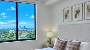 A modern bedroom with a large bed, a nightstand, a lamp, and framed artwork on the wall. - Modern Miami 2BR with Skyline Views (Miami)