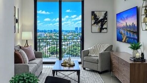 A modern living room with a dining area, large windows, and a city view. - Modern Miami 2BR with Skyline Views (Miami)