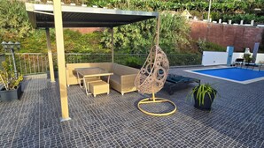 Eine Dachterrasse mit Pool, Gartenmöbeln und einer Hängematte.