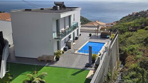 Ein modernes Gebäude mit Pool auf dem Dach, einer Glasbrüstung und Blick aufs Meer.
