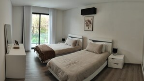 Ein Hotelzimmer mit zwei Betten, einem Schreibtisch, einem Stuhl, einem Fernseher und einem Fenster mit Vorhängen.