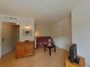 A living room with a wooden cabinet, a red sofa, a small table, and a television on a stand. - Ground floor, terrace, parking, tv, ski locker, 37m², Le Grand Bornand (Le Grand-Bornand)
