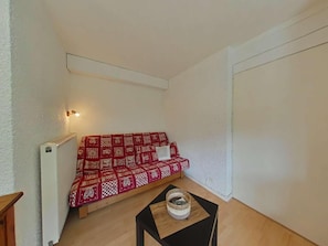 A small, enclosed room with a sofa, a radiator, and a small table with a basket. - Ground floor, terrace, parking, tv, ski locker, 37m², Le Grand Bornand (Le Grand-Bornand)