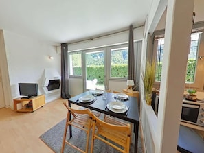 A modern dining area with a black table set for two, a television on a stand, and a fireplace. - Ground floor, terrace, parking, tv, ski locker, 37m², Le Grand Bornand (Le Grand-Bornand)