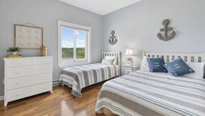Un dormitorio con dos camas, un tocador, una ventana y elementos decorativos en la pared.