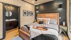 Una camera da letto moderna con una testiera in legno, un comodino con un vassoio di snack e uno specchio sopra il mobiletti.