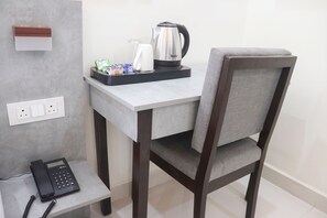 A small, modern kitchenette with a coffee maker, a kettle, and a tray with packaged food. - OnlyStay Business Suites Hitech city (Hyderabad)