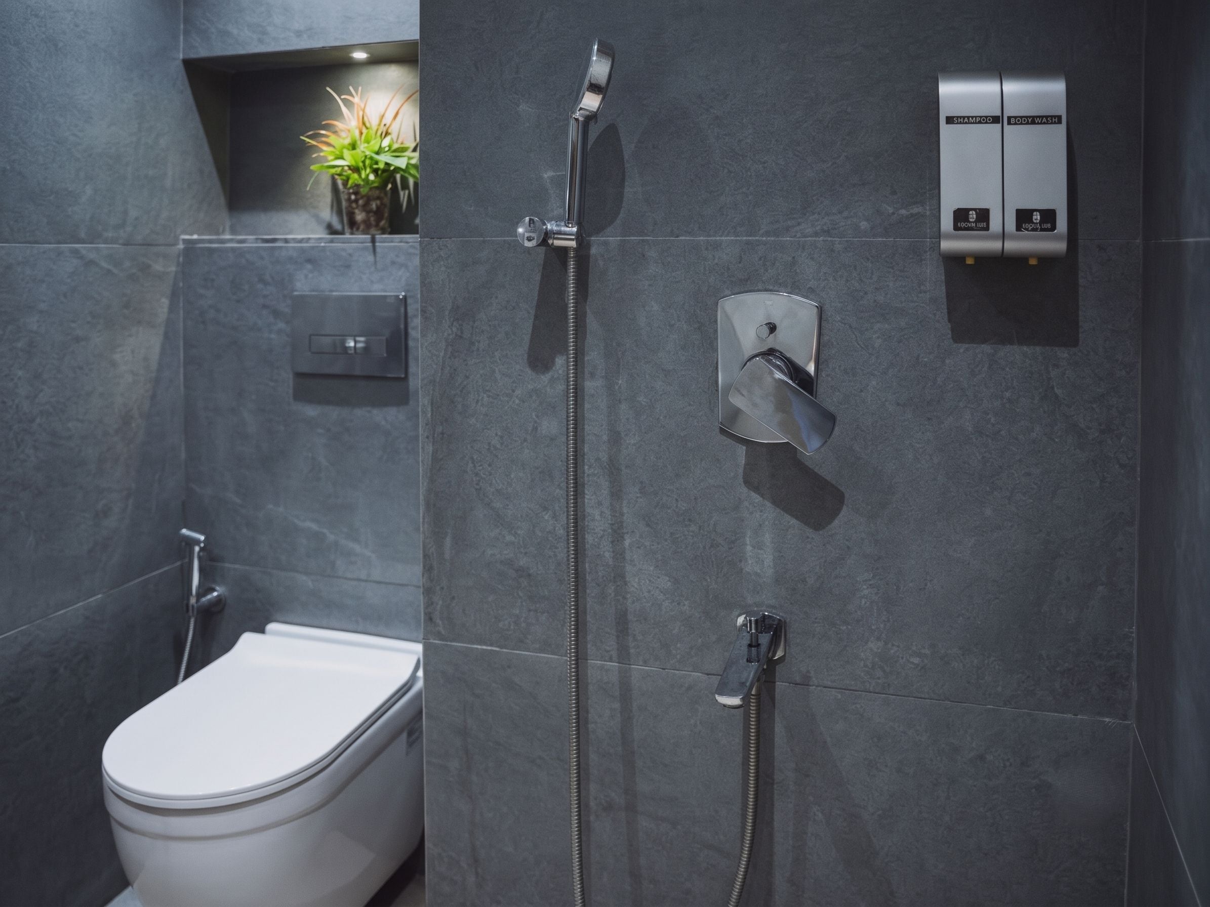 Un baño moderno con inodoro, ducha y panel de control para agua y temperatura.