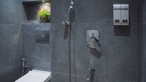 Moderni kylpyhuone, jossa on wc, suihku ja ohjauspaneeli veden ja lämpötilan säätämistä varten.