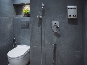 Une salle de bain moderne équipée de toilettes, d’une douche et d’un panneau de commande pour régler le débit et la température de l’eau.