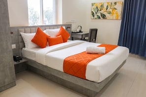 Une chambre d’hôtel avec un lit, un bureau, une chaise, un téléphone et un tableau au mur.
