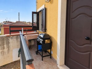 Een balkon met een barbecue, een spoelbak en een deur.
