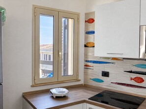 Een moderne keuken met een groot raam, een toilet en een spatwand met tekeningen van vissen.