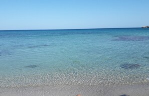 A beach with clear shallow water and a distant rocky outcrop. - The sea and the sun: The beach is within walking distance, and the house is comfortable and bright—everything is within easy reach. (Unknown)