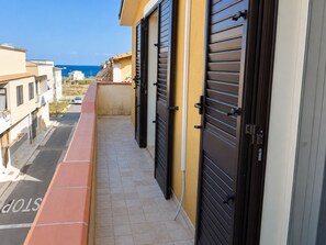 A balcony with a view of the sea, a tiled floor, and a building with a yellow facade and black shutters. - The sea and the sun: The beach is within walking distance, and the house is comfortable and bright—everything is within easy reach. (Unknown)