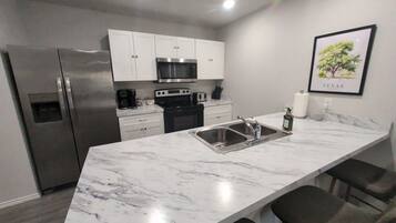 A modern kitchen with a marble countertop, stainless steel appliances, and a sink.
