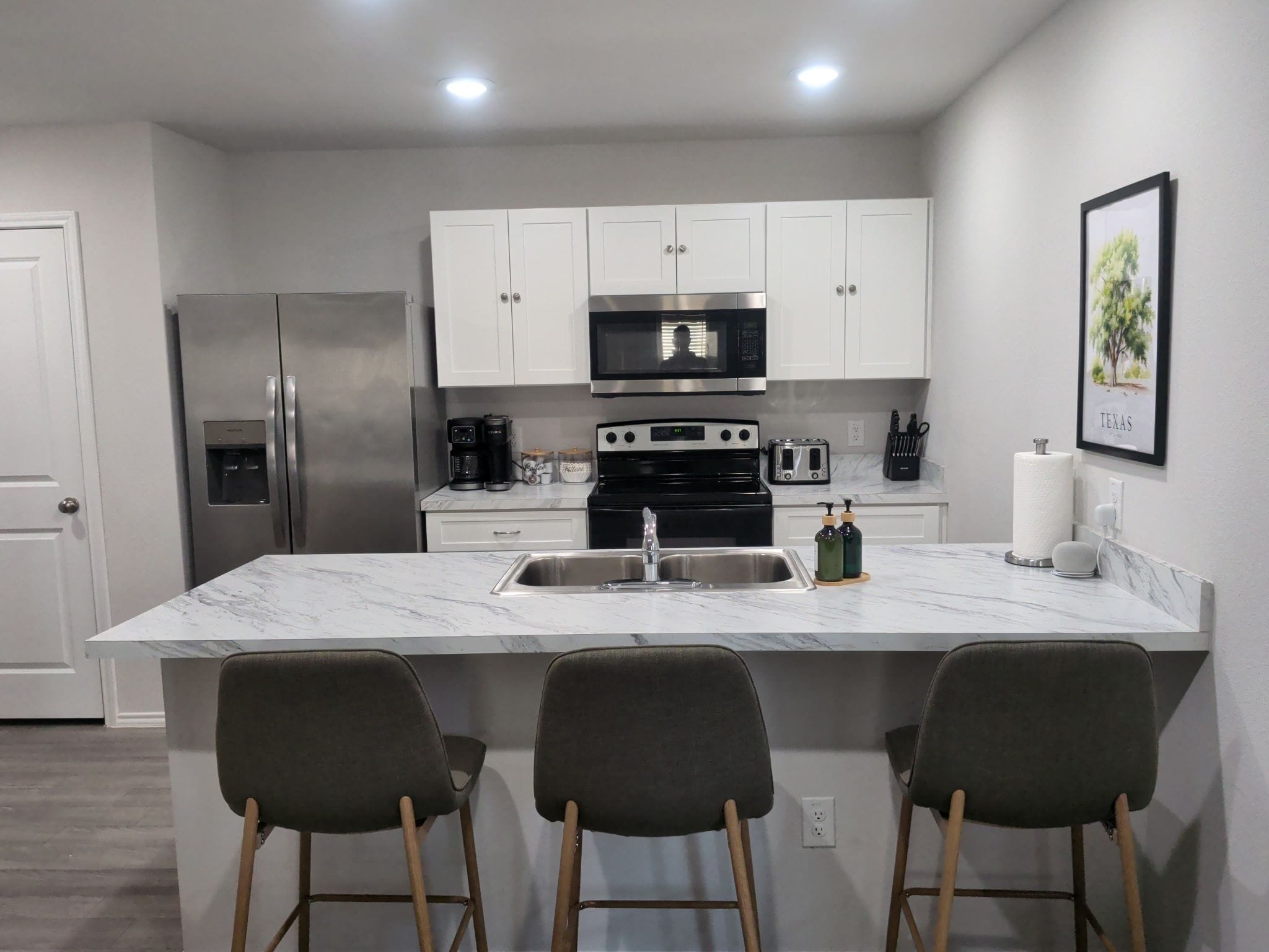 A modern kitchen with a central island, stainless steel appliances, and bar stools.