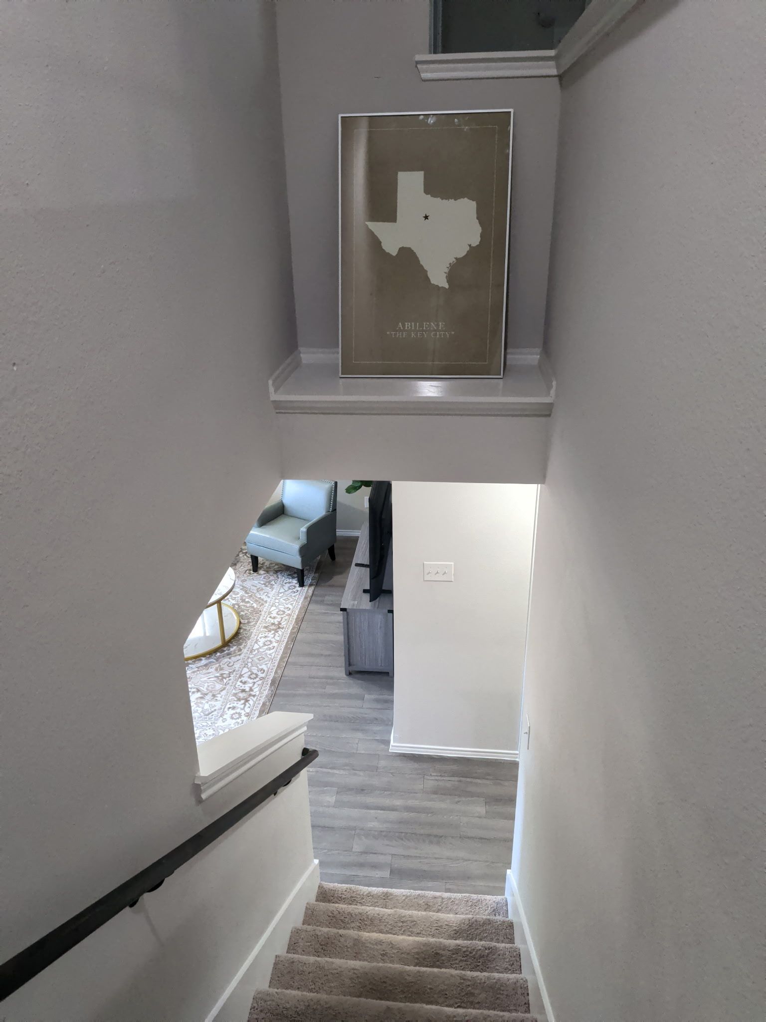 A staircase leading to a living area with a framed map on the wall.
