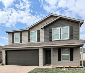 A two-story house with a garage, a front porch, and a small front yard.