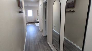 A hallway with a wooden floor, white walls, and a door at the end.
